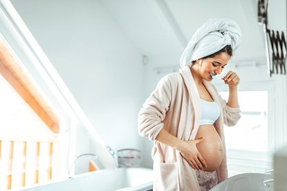 Femme enceinte qui se brosse les dents en regardant son ventre - Les effets de la grossesse sur la santé buccodentaire + Quelques conseils